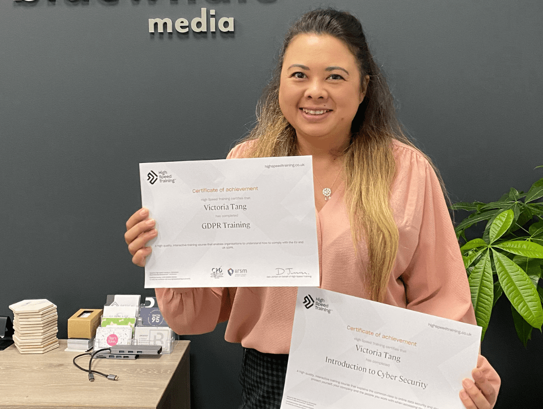 Victoria Tang holding a certificate for achievement in GDPR training and a certificate of achievement in Cyber Security