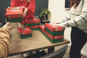 Lucy Bennett, Naomi Clarke and Ben Smart preparing Operation Christmas Child boxes for delivery.